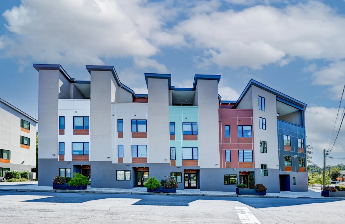 A vibrant exterior view of the property featuring a colorful facade, large modern windows, and striking architectural design. The setting suggests an urban environment ideal for community events and casual gatherings.