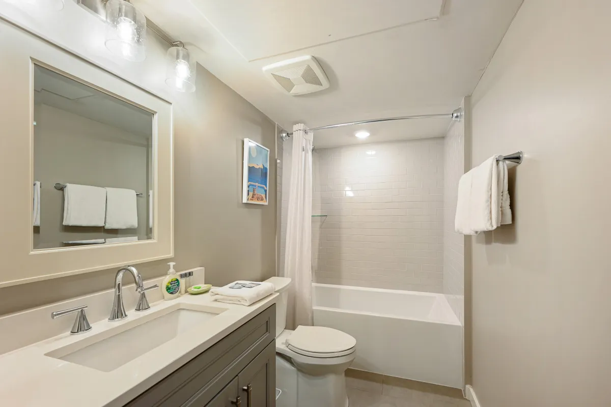 A bright, refreshing bathroom with a vanity, large mirror, soaking bathtub, fluffy towels, and soothing wall art. The space is designed for both relaxation and daily routines, embodying the idea of rejuvenation and convenience.