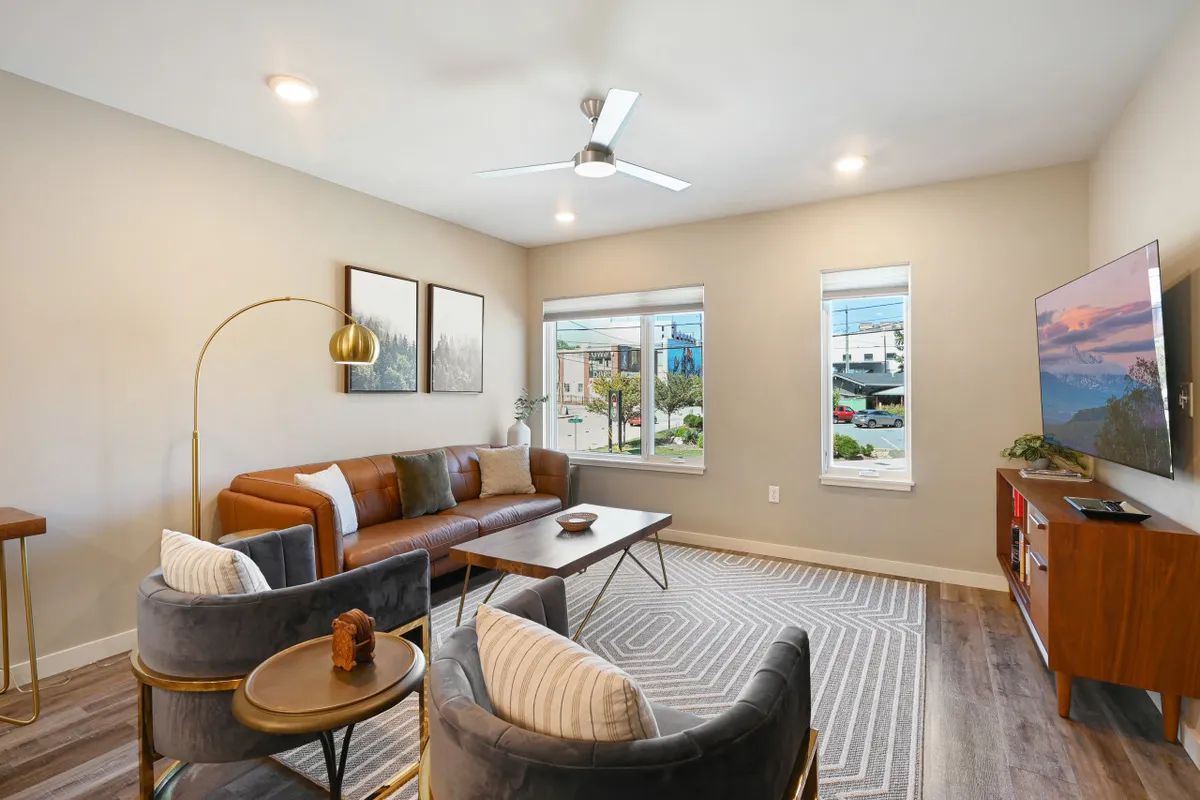 An inviting interior sitting area with a leather sofa, coffee table, modern artwork, and windows that hint at an elevated view. The room exudes comfort and style, making it ideal for relaxing indoors while still feeling connected to the outdoor ambiance.