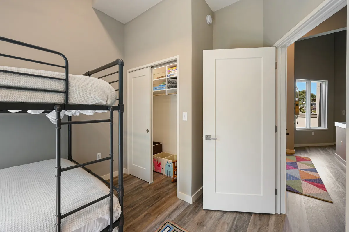 A cheerful interior shot of a kids’ bunk room featuring a bunk bed, colorful rug, and closet door, evoking a playful, welcoming mood ideal for family stays.