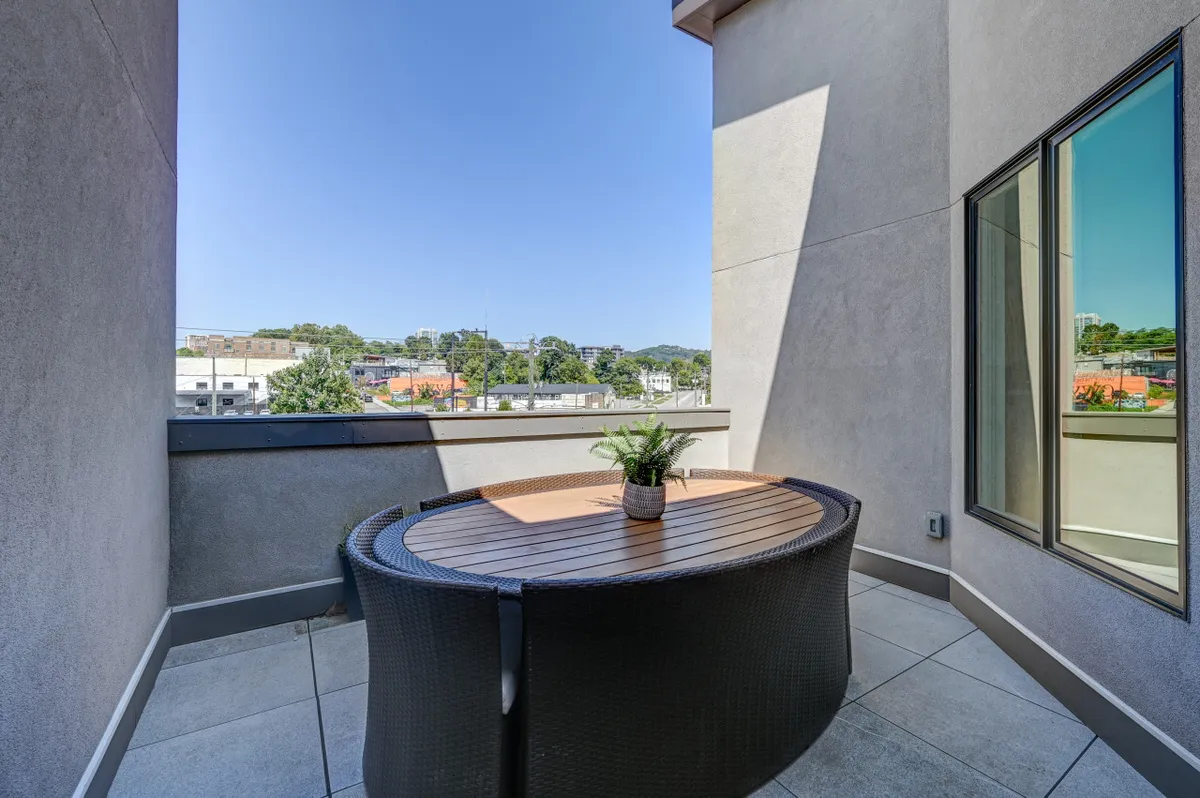 This exterior image features a rooftop terrace with a circular table, a potted plant, and a serene view of the surrounding area. The vantage point highlights the elevated setting and openness, ideal for relaxation or social gatherings while enjoying city views and sunsets.