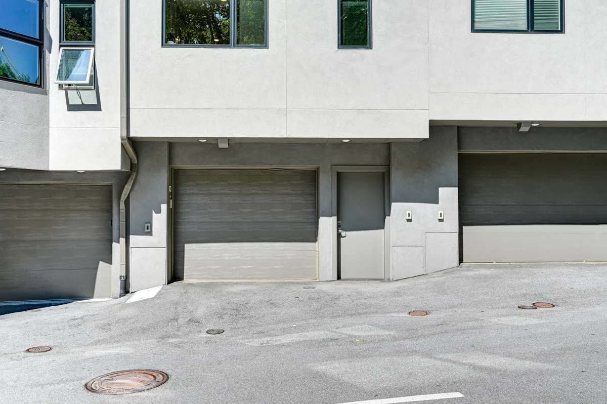 A contemporary exterior perspective focusing on the garage doors, entrance, and crisp window lines. The image conveys functionality and ease of access, ideal for arrivals and departures.