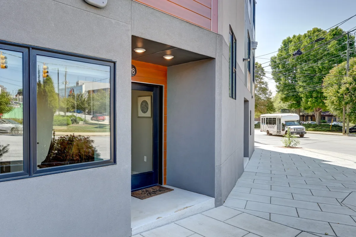 A striking modern entrance with large windows and contrasting materials, giving a sense of transitioning from the city's buzz to a private, stylish home retreat.
