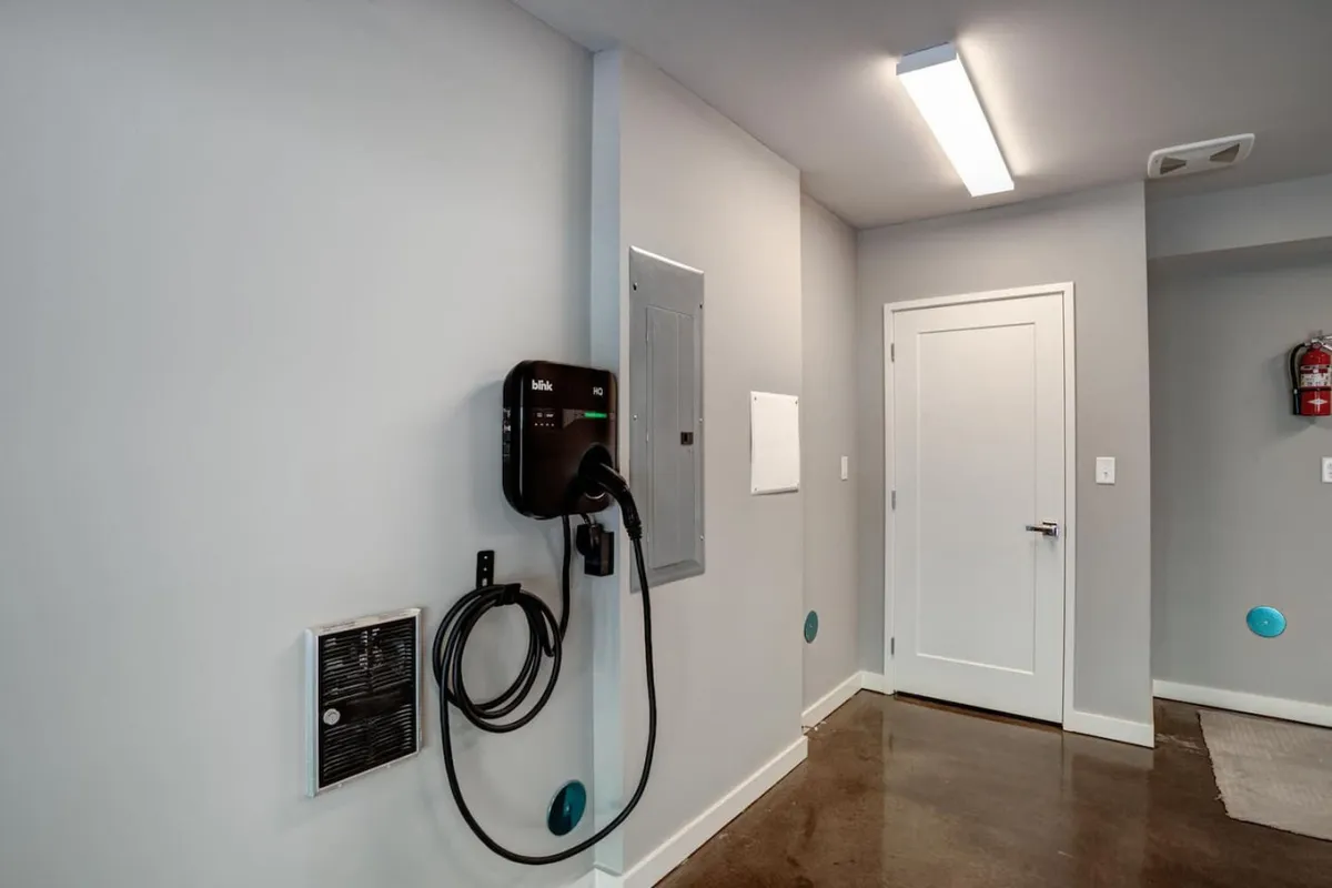 This image depicts a modern garage setup featuring an electric vehicle charger mounted on the wall and a sleek concrete floor. The space is organized and clean, designed for practical use and efficient storage.